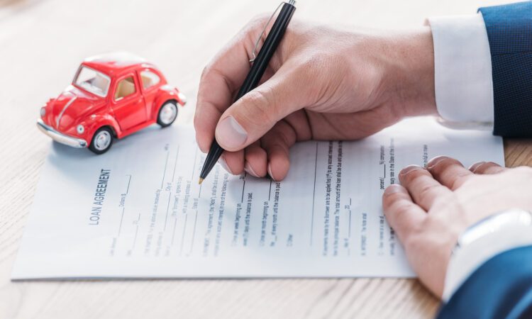 view of car dealer writing in loan agreement